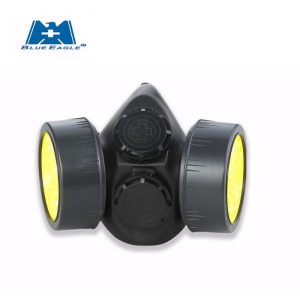 A Blue Eagle NP-306 black twin-cartridge half-face respirator showing the dual side-mounted filter ports, central exhalation valve, and the four-point adjustable head harness.